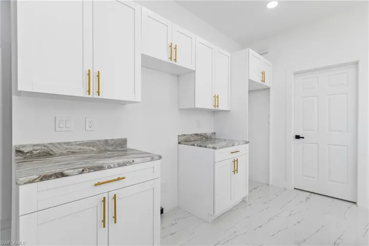 Kitchen featuring white cabinets, light marble finish flooring, recessed lighting, and light stone countertops