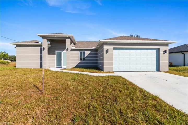 View of front of house featuring a front lawn, driveway, stucco siding, and a garage