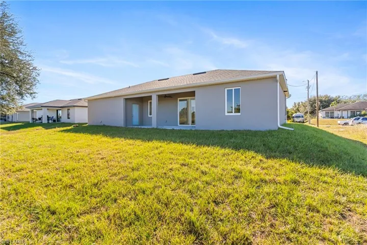 Rear view of property featuring a lawn, a patio area, stucco siding, and ceiling fan