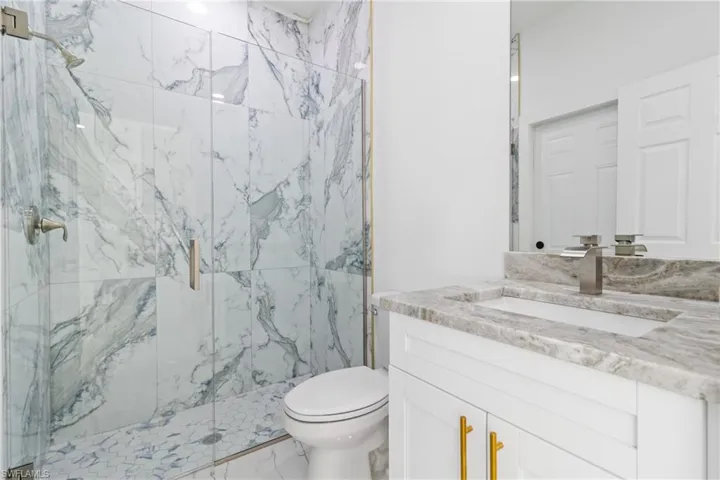 Bathroom featuring vanity, a marble finish shower, and marble finish floors