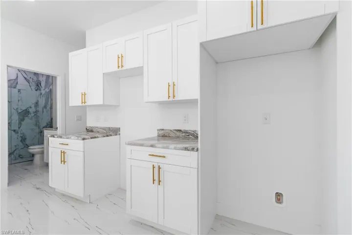 Kitchen featuring white cabinets and light marble finish floors