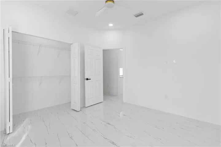 Unfurnished bedroom with a ceiling fan, a closet, recessed lighting, and light marble finish floors
