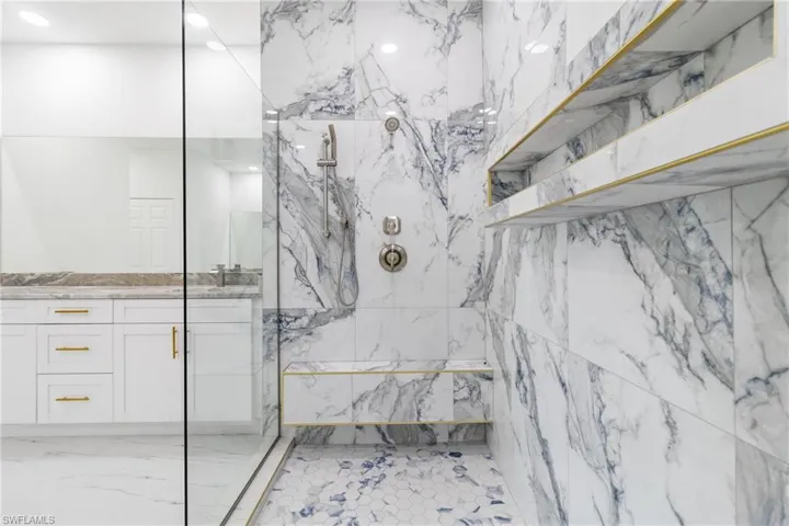 Full bathroom featuring a marble finish shower and vanity