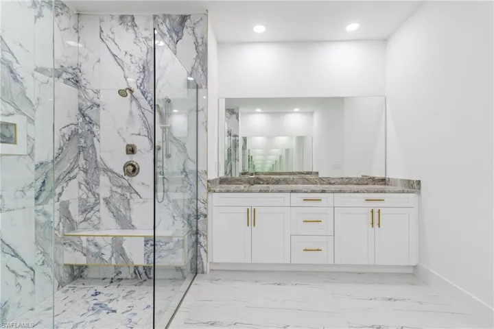 Bathroom with a marble finish shower, vanity, recessed lighting, and light marble finish flooring