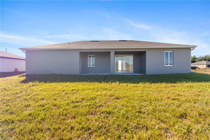 Rear view of house with a patio area, stucco siding, and a yard