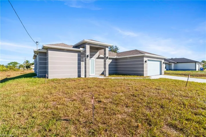 View of front of home with a front yard, an attached garage, stucco siding, and concrete driveway