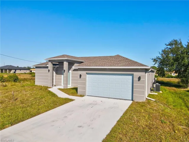 View of front of house with a front yard, driveway, a shingled roof, stucco siding, and a garage