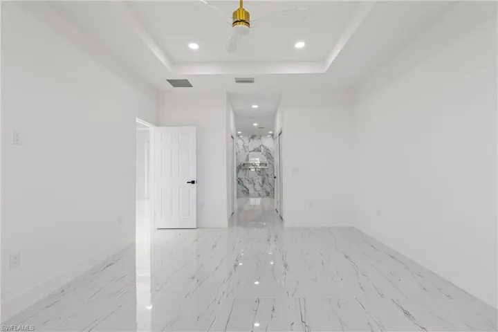 Spare room with recessed lighting, ceiling fan, light marble finish flooring, and a raised ceiling