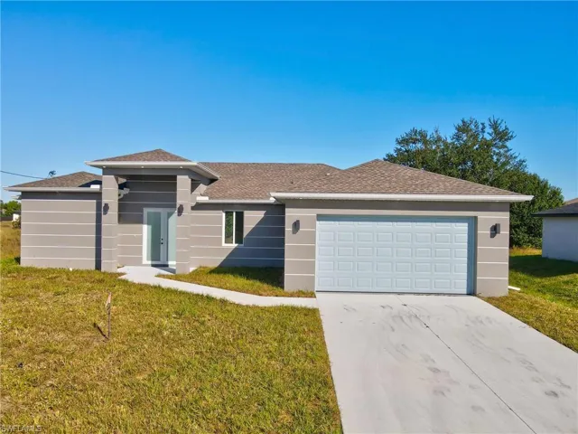View of front of home featuring a front yard, driveway, roof with shingles, an attached garage, and stucco siding