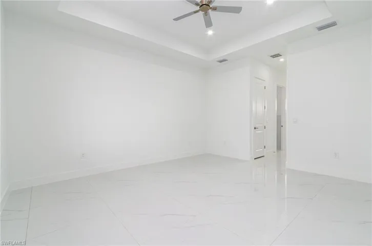 Spare room with baseboards, visible vents, a raised ceiling, and ceiling fan