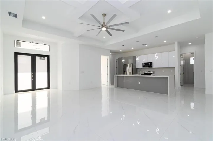 Unfurnished living room with recessed lighting, coffered ceiling, visible vents, a ceiling fan, and a tray ceiling