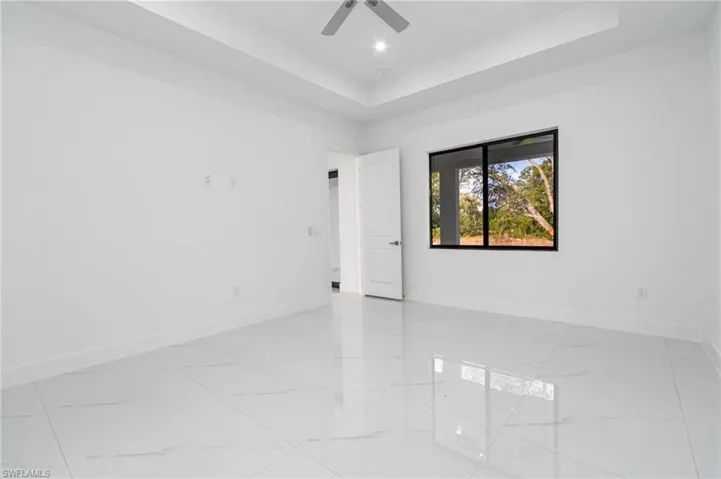 Master room with recessed lighting, ceiling fan, a tray ceiling, marble finish floor, and baseboards
