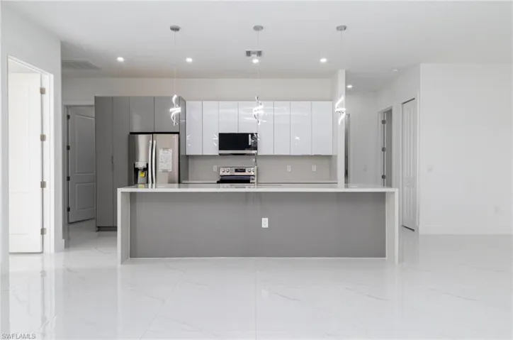 Kitchen with white cabinetry, a spacious island, stainless steel appliances, recessed lighting, and modern cabinets