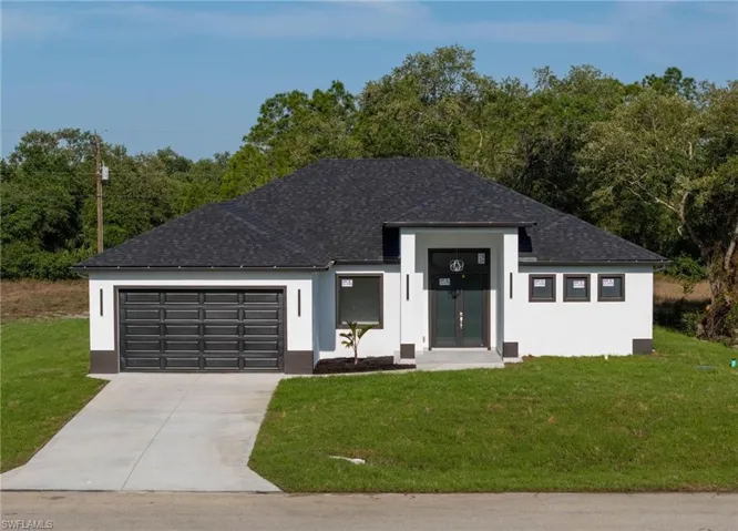 View of front of property with concrete driveway, a front lawn, a garage, and stucco siding