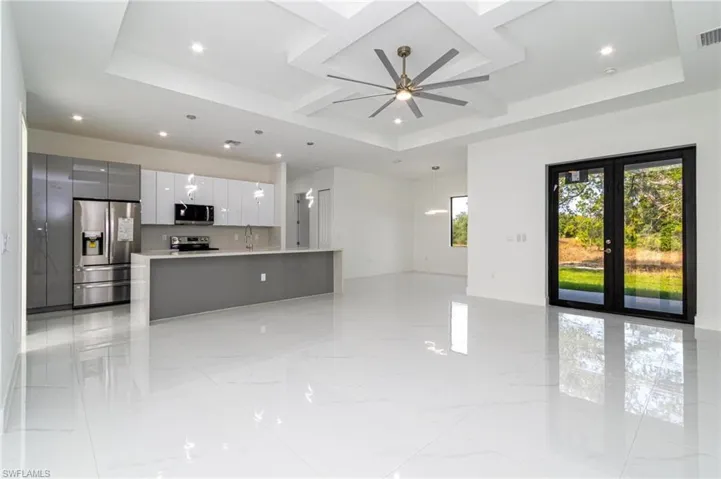 Unfurnished living room with recessed lighting, a ceiling fan, visible vents, and a tray ceiling