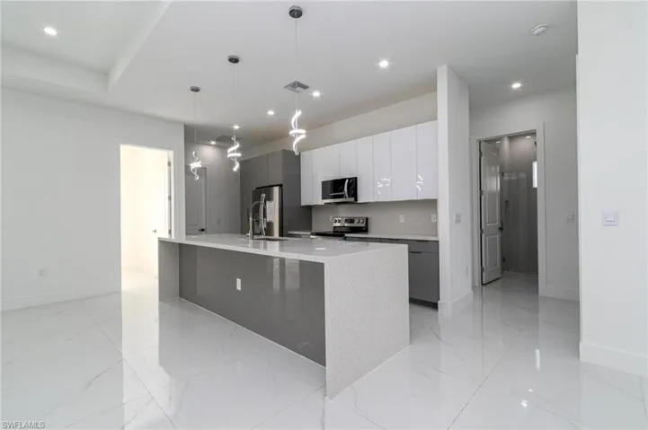 Kitchen with a sink, modern cabinets, visible vents, baseboards, and appliances with stainless steel finishes