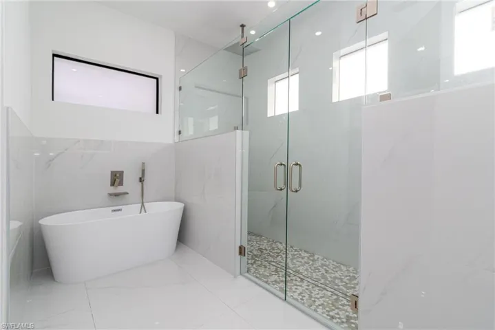 Full bath featuring a freestanding bath and a marble finish shower
