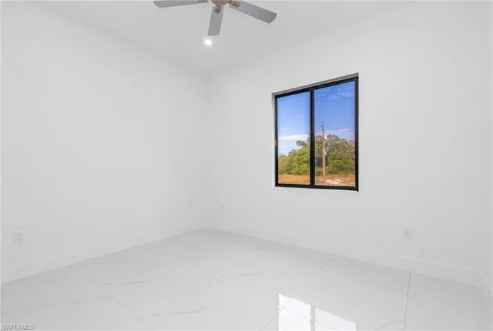 Spare room featuring marble finish floor, ceiling fan, and baseboards