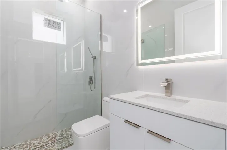 Bathroom featuring vanity, toilet, and a marble finish shower