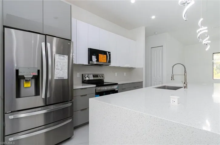 Kitchen featuring modern cabinets, a sink, appliances with stainless steel finishes, and white cabinetry