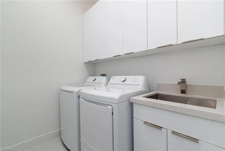Washroom with a sink, washing machine and clothes dryer, and cabinet space