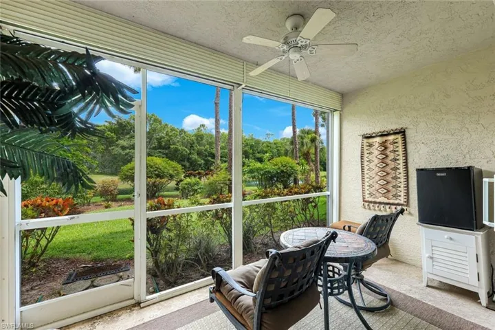 Screened lanai featuring a ceiling fan, textured wall finish, and a natural landscape beyond