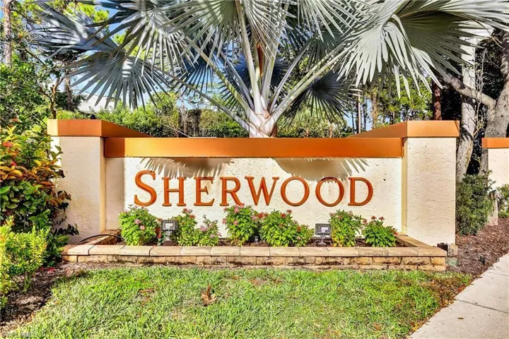 Stone-clad entry monument featuring "SHERWOOD" lettering, accented by a mature palm tree and low-lying shrubs