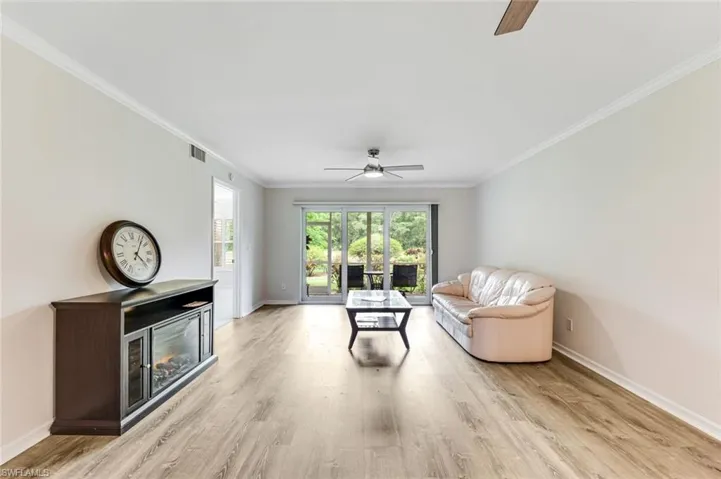 Spacious room featuring wood-finish flooring, white crown molding, and light-toned walls