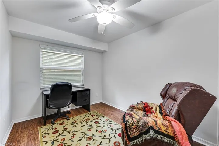 Room featuring wood-finish flooring, a window with horizontal blinds, and a white ceiling fan with integrated lighting