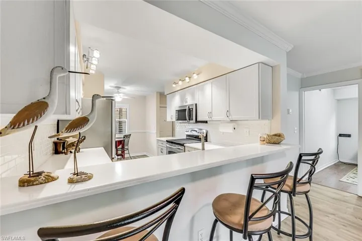 Modern kitchen featuring white cabinetry, a white subway tile backsplash, stainless steel appliances, and wood-finish flooring