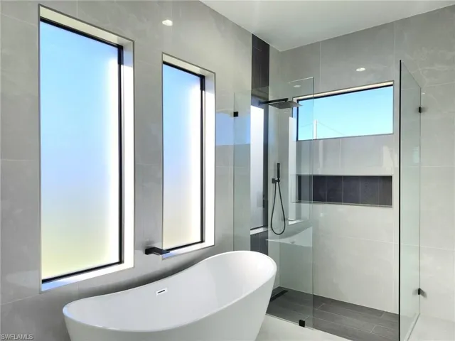 Full bathroom featuring a soaking tub, a walk in shower, and tile walls
