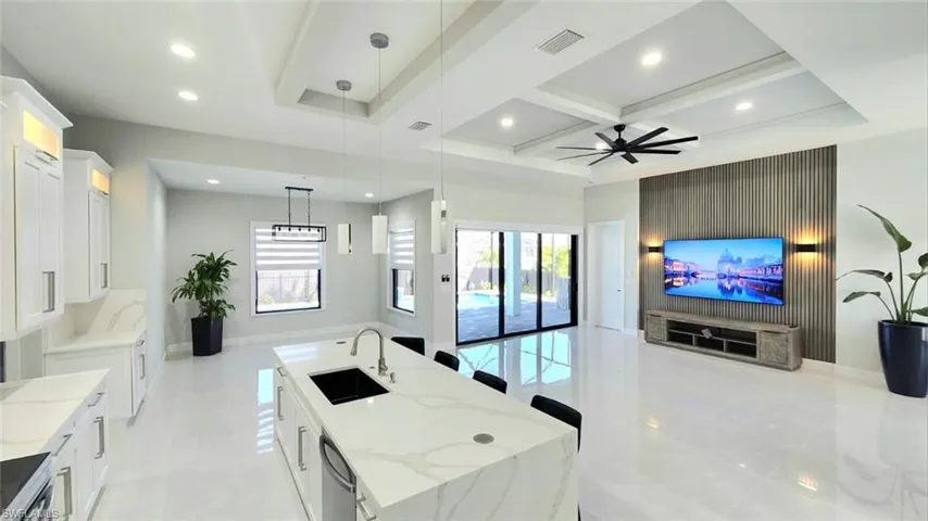 Kitchen featuring light stone counters, a large island, white cabinets, open floor plan, and pendant lighting
