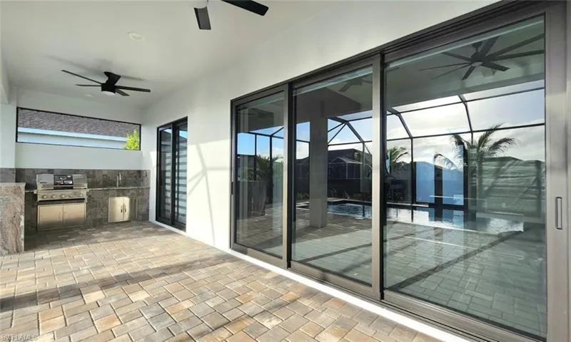 View of patio / terrace with a ceiling fan, exterior kitchen, an outdoor pool, and a lanai