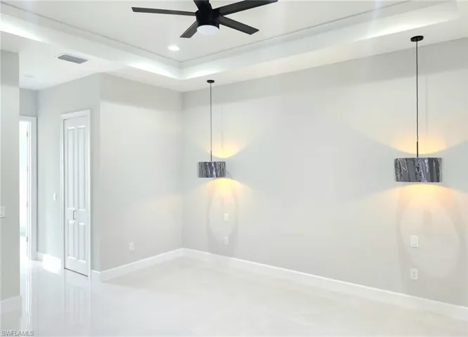 Empty room featuring a raised ceiling, recessed lighting, and a ceiling fan