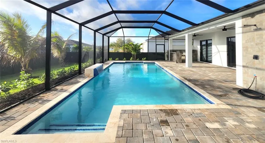 View of swimming pool with patio surround, a sunroom, a lanai, and an outdoor kitchen
