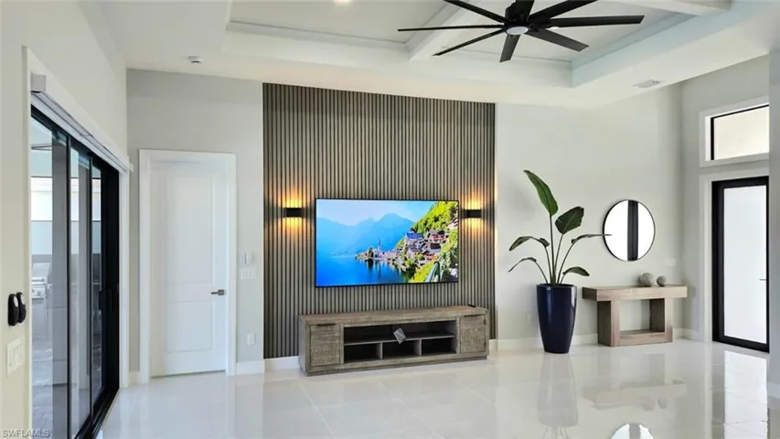 Living room with healthy amount of natural light, light tile patterned floors, and a ceiling fan