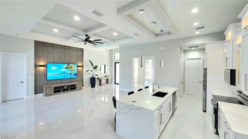 Kitchen featuring a spacious island, white cabinetry, open floor plan, stainless steel appliances, and coffered ceiling