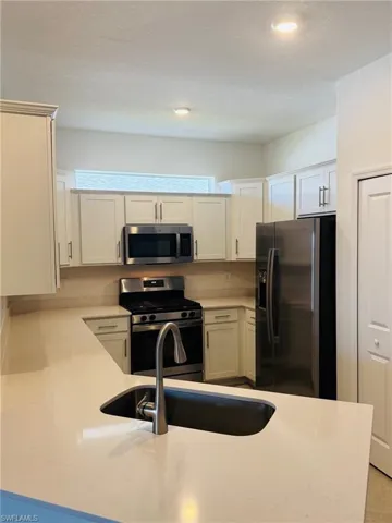 Kitchen with sink, a wealth of natural light, a textured ceiling, and appliances with stainless steel finishes