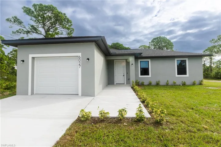 Ranch-style house with stucco siding, an attached garage, a front yard, and concrete driveway