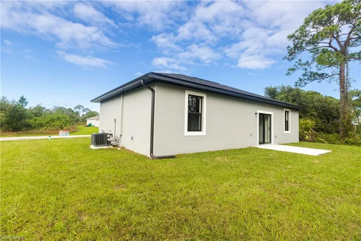 Rear view of property with a lawn, stucco siding, and a patio