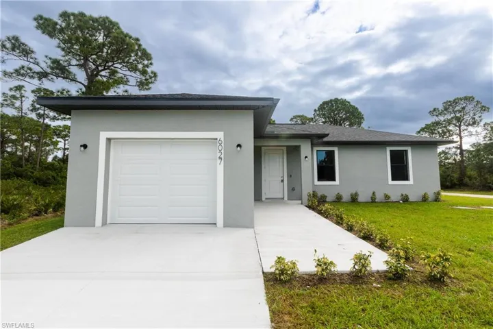 View of front of property featuring stucco siding, an attached garage, concrete driveway, and a front yard