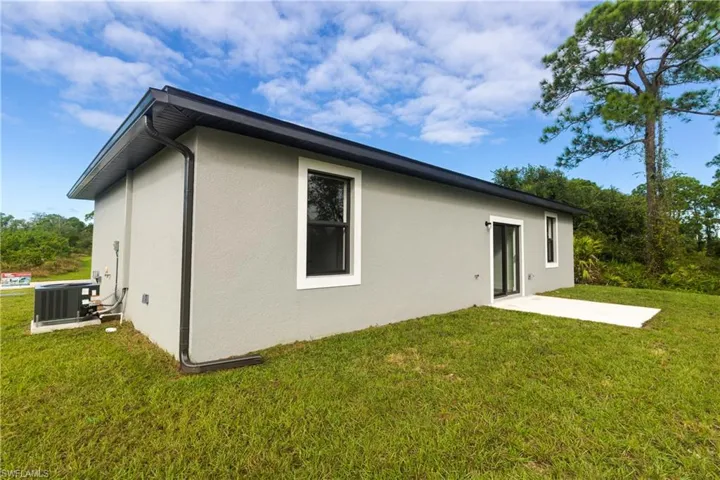 Back of property featuring a patio area, stucco siding, and a lawn