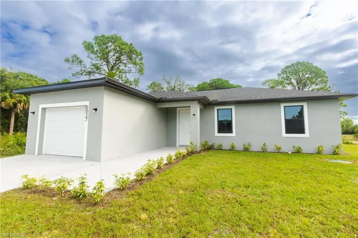 Ranch-style home with a garage, stucco siding, a front lawn, and concrete driveway