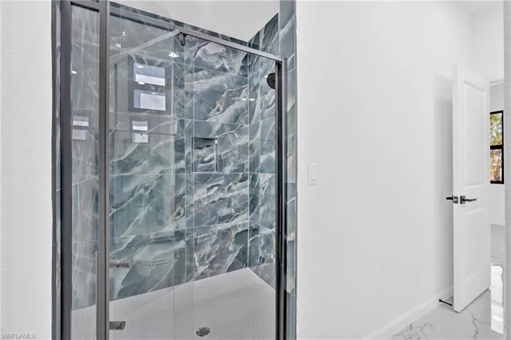 Full bathroom with a marble finish shower and marble look tiles
