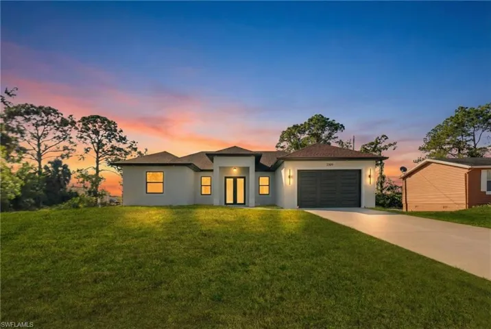 View of front of house with stucco siding, a yard, and concrete driveway