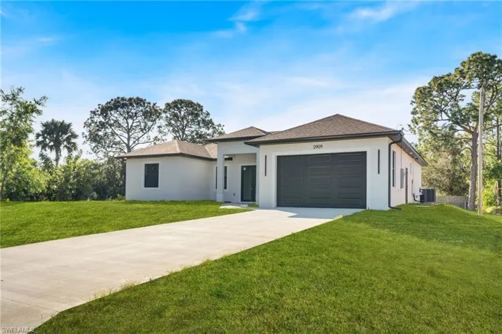View of front facade with driveway, a front lawn, stucco siding, and a garage