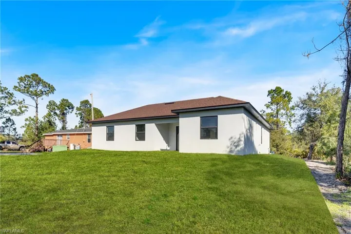 Back of house featuring stucco siding and a yard