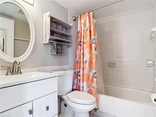 Bathroom with shower / bath combo with shower curtain, vanity, and toilet