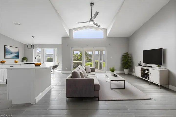 Living area with a ceiling fan, high vaulted ceiling, wood tiled floors, and a chandelier