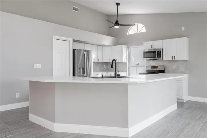 Kitchen featuring light countertops, a sink, white cabinetry, appliances with stainless steel finishes, and visible vents